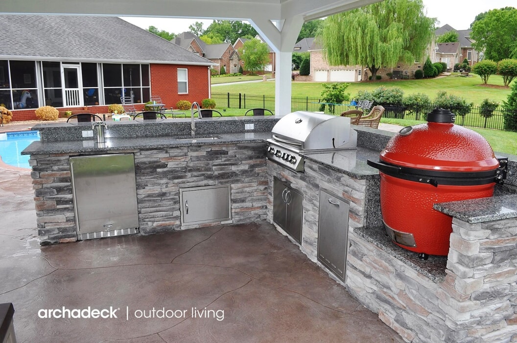 Backyard outdoor kitchen featuring a grill, sink, and storage.